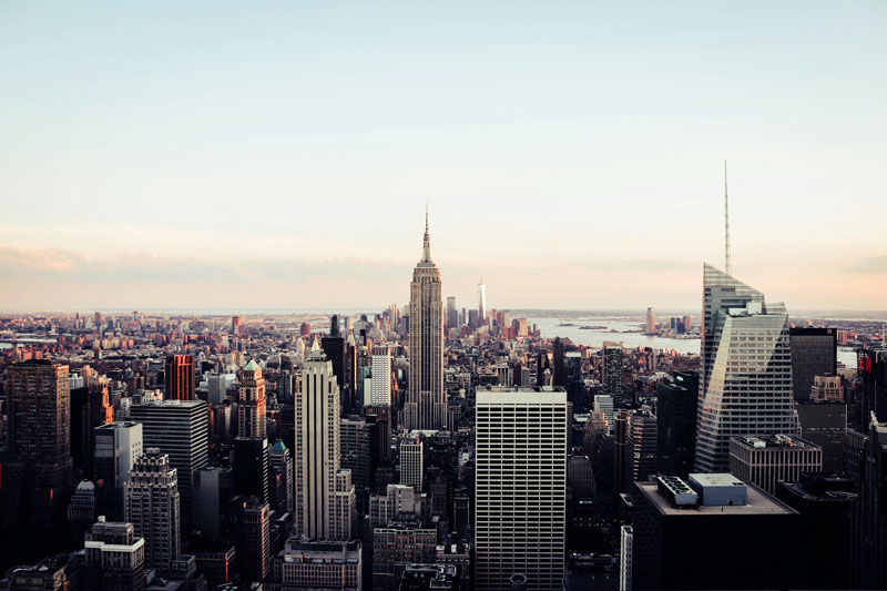 Aerial view of the New York City skyline featuring the Empire State Building with surrounding skyscrapers under a clear sky.