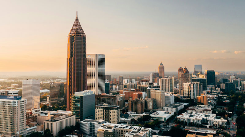 Aerial view of the Atlanta skyline at sunset featuring downtown skyscrapers under a clear evening sky.