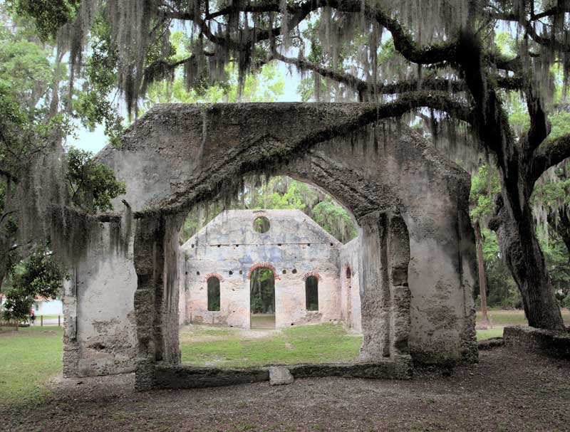 Ruins of the historic Chapel of Ease on St. Helena Island, framed by large oak trees draped in Spanish moss.